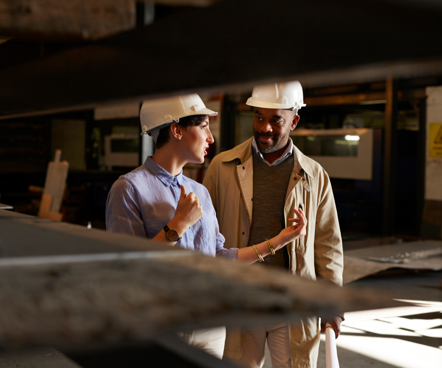 Man and woman in hardhats talking at work